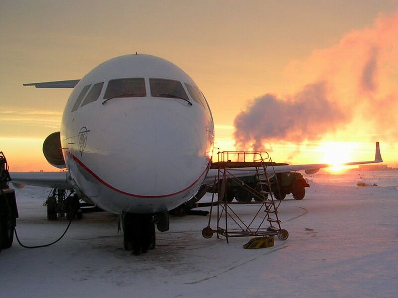 Airplane on snowy tarmac at sunset