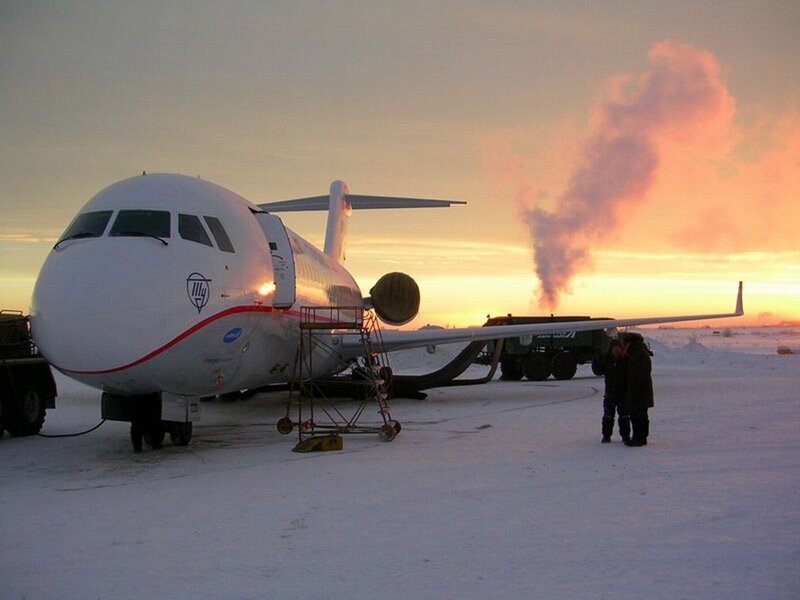 Airplane on snowy tarmac at sunset
