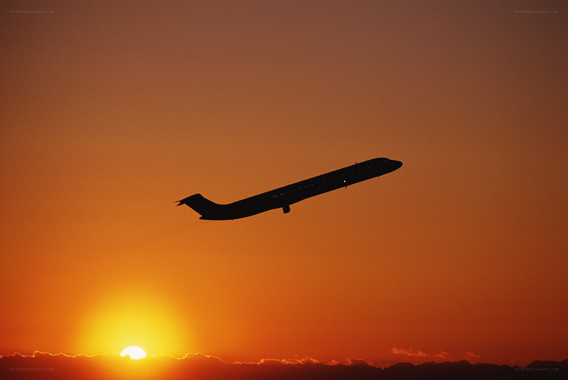 Airplane silhouetted against sunset