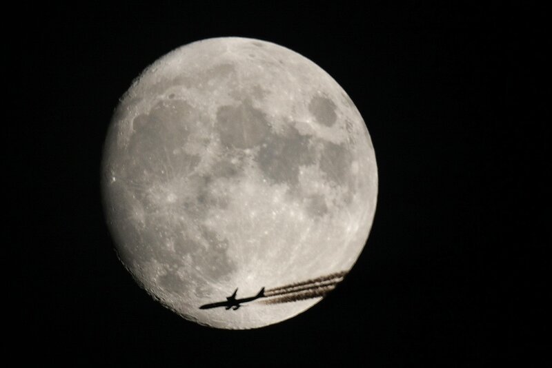 Airplane silhouetted against the moon