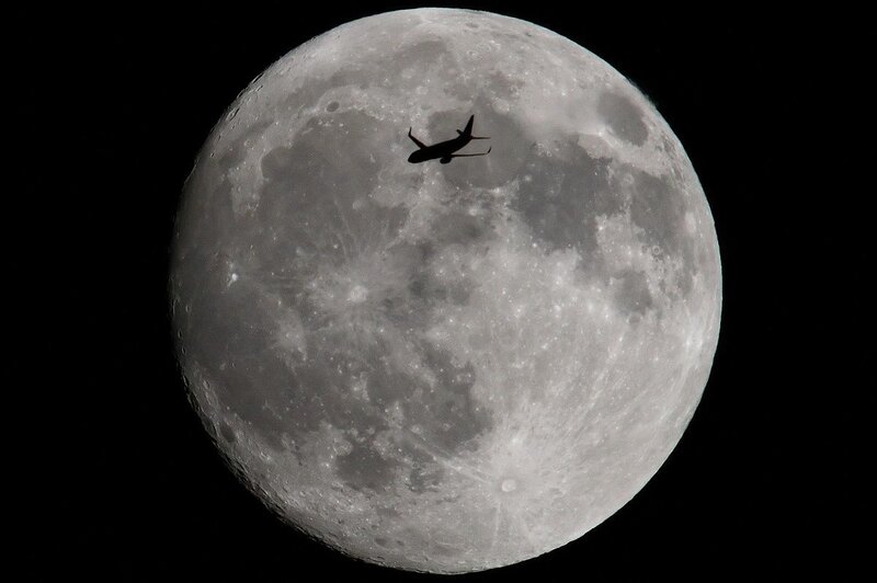 Airplane silhouetted against the moon
