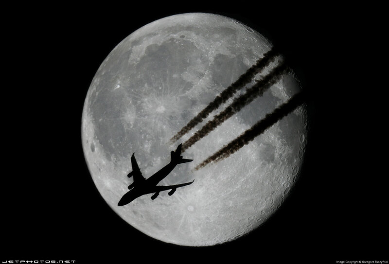 Airplane silhouetted against the moon