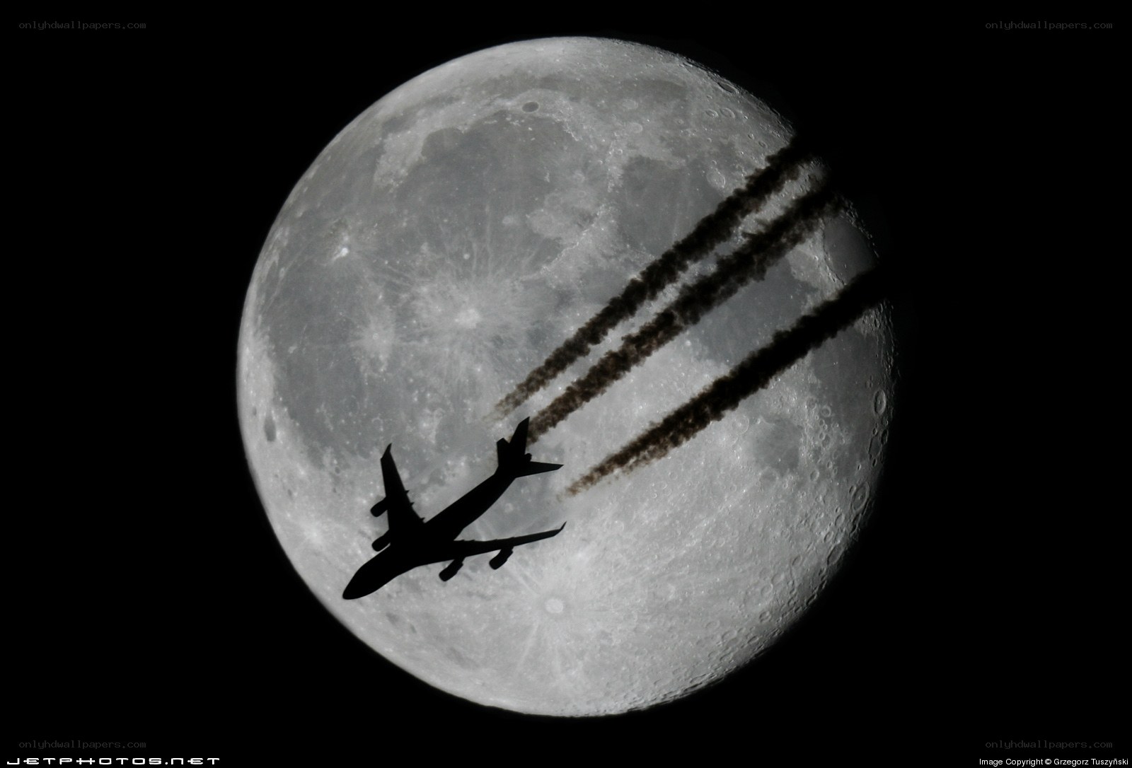 Airplane silhouetted against the moon