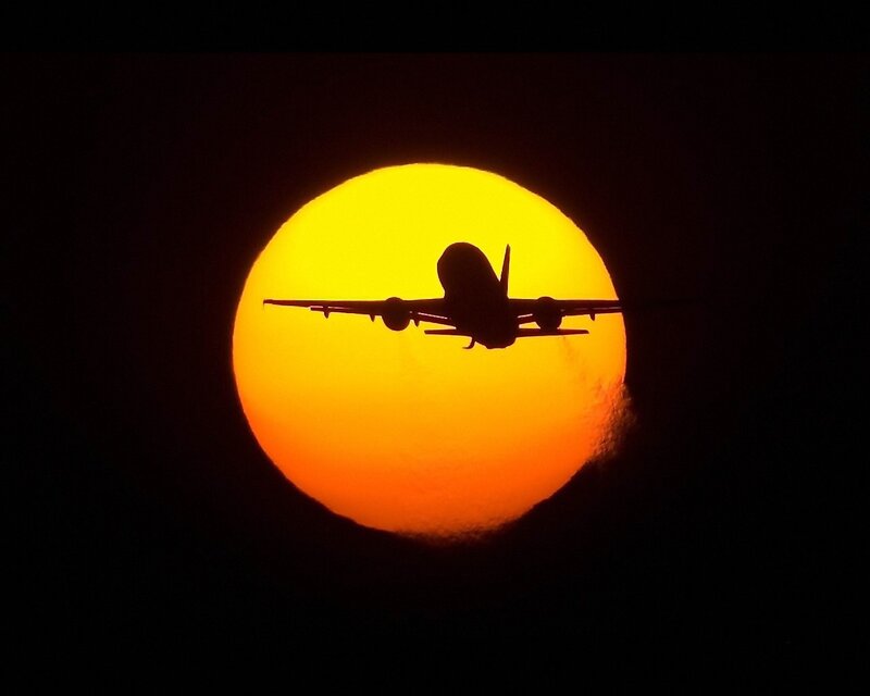 Airplane silhouetted against the sun