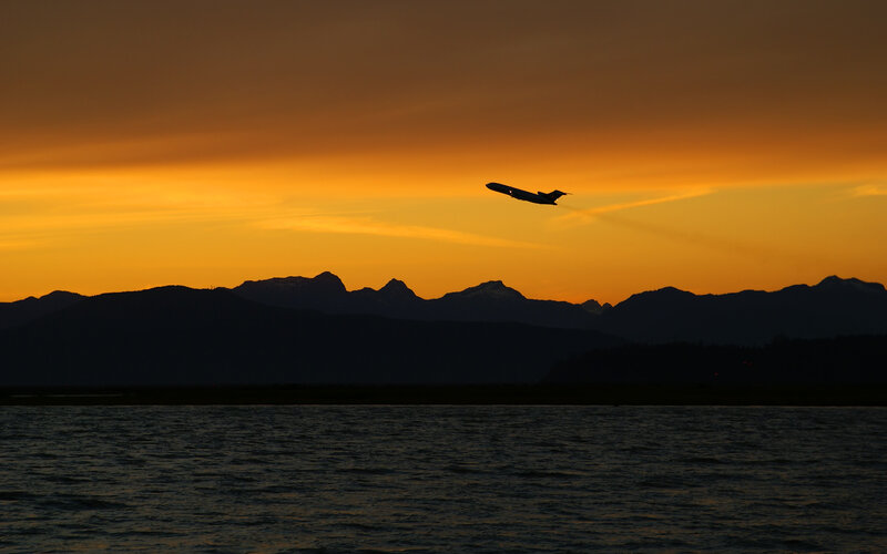 Airplane silhouetted at sunset