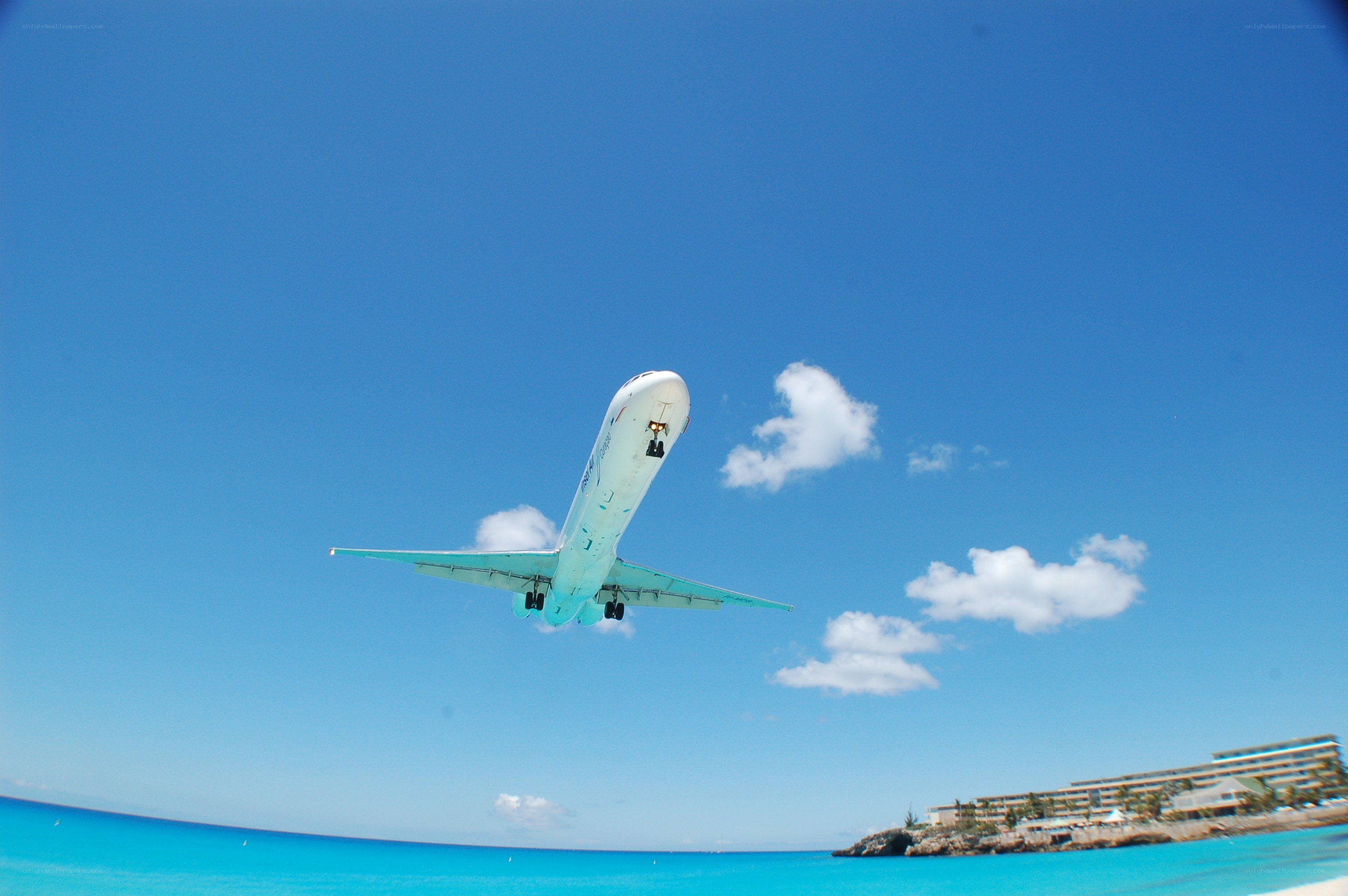 Airplane taking off over tropical coast
