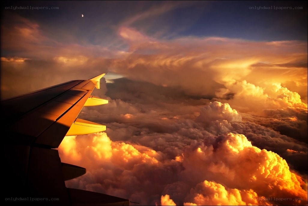 Airplane wing above clouds at sunset
