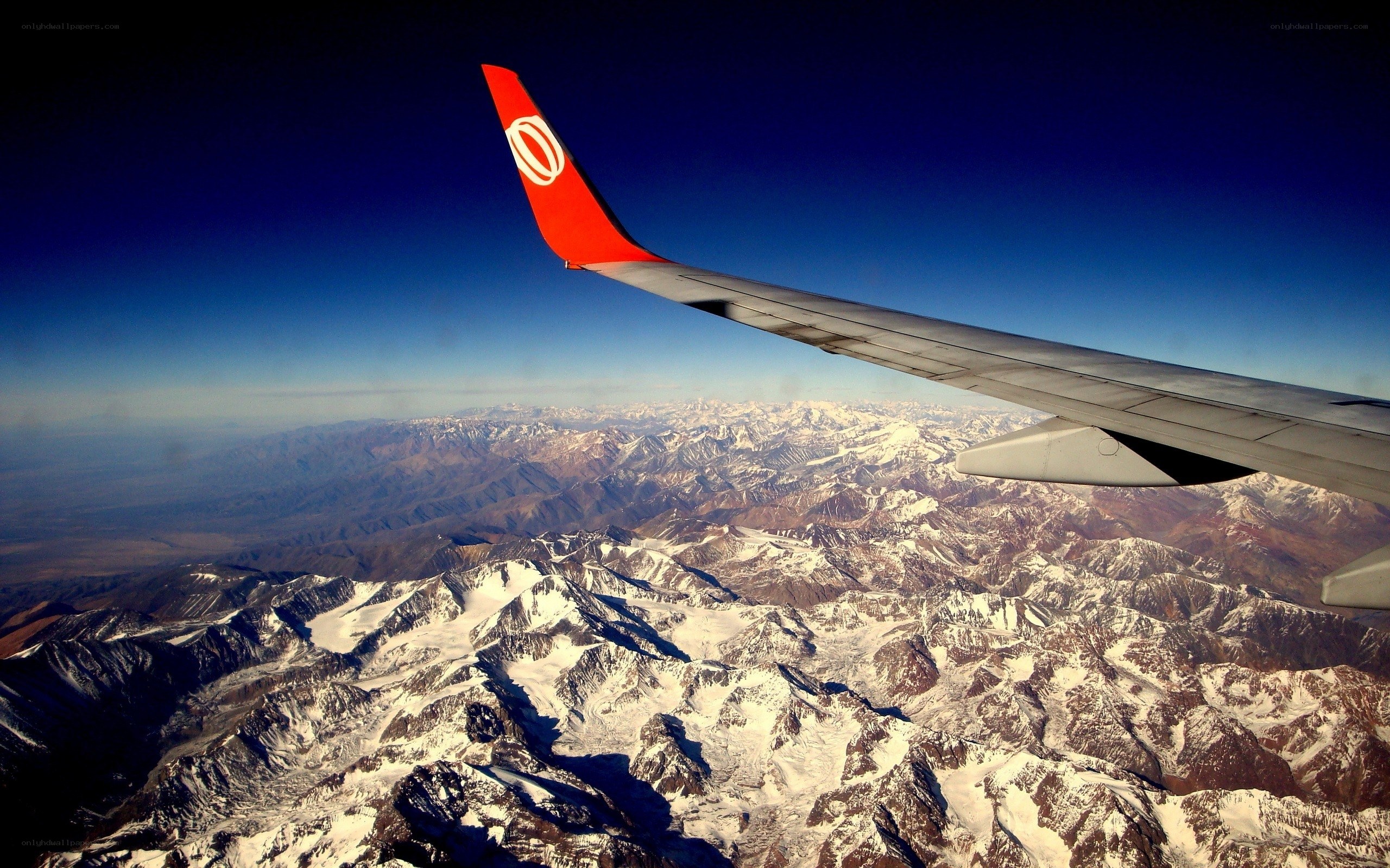 Airplane wing over snowy mountains
