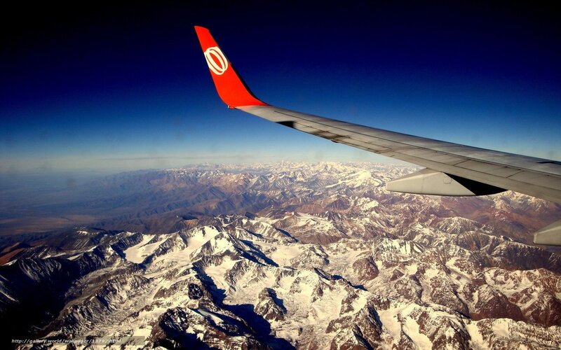 Airplane wing over snowy mountains