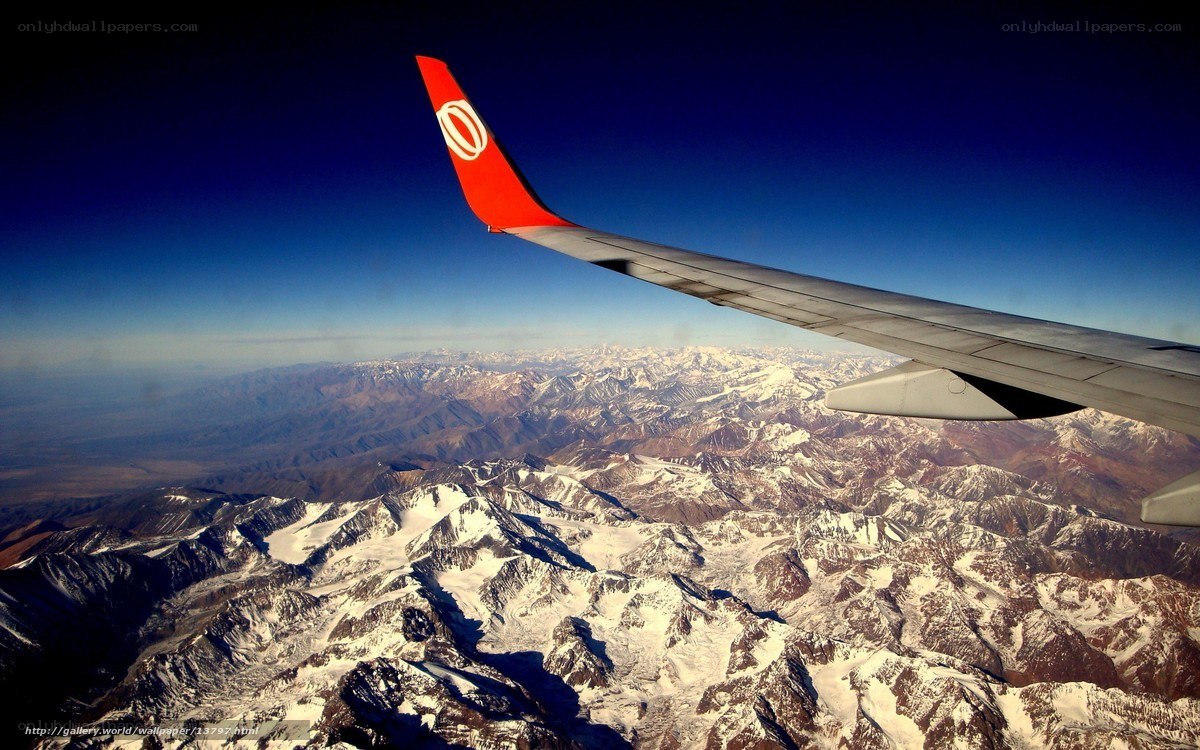 Airplane wing over snowy mountains