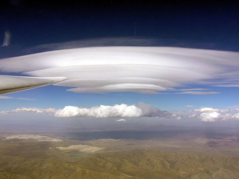 airplane wing with lenticular clouds