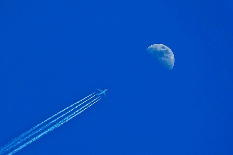 Airplane with contrails near the moon