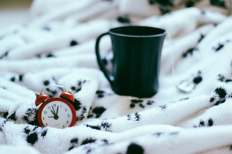 Alarm clock and mug on blanket