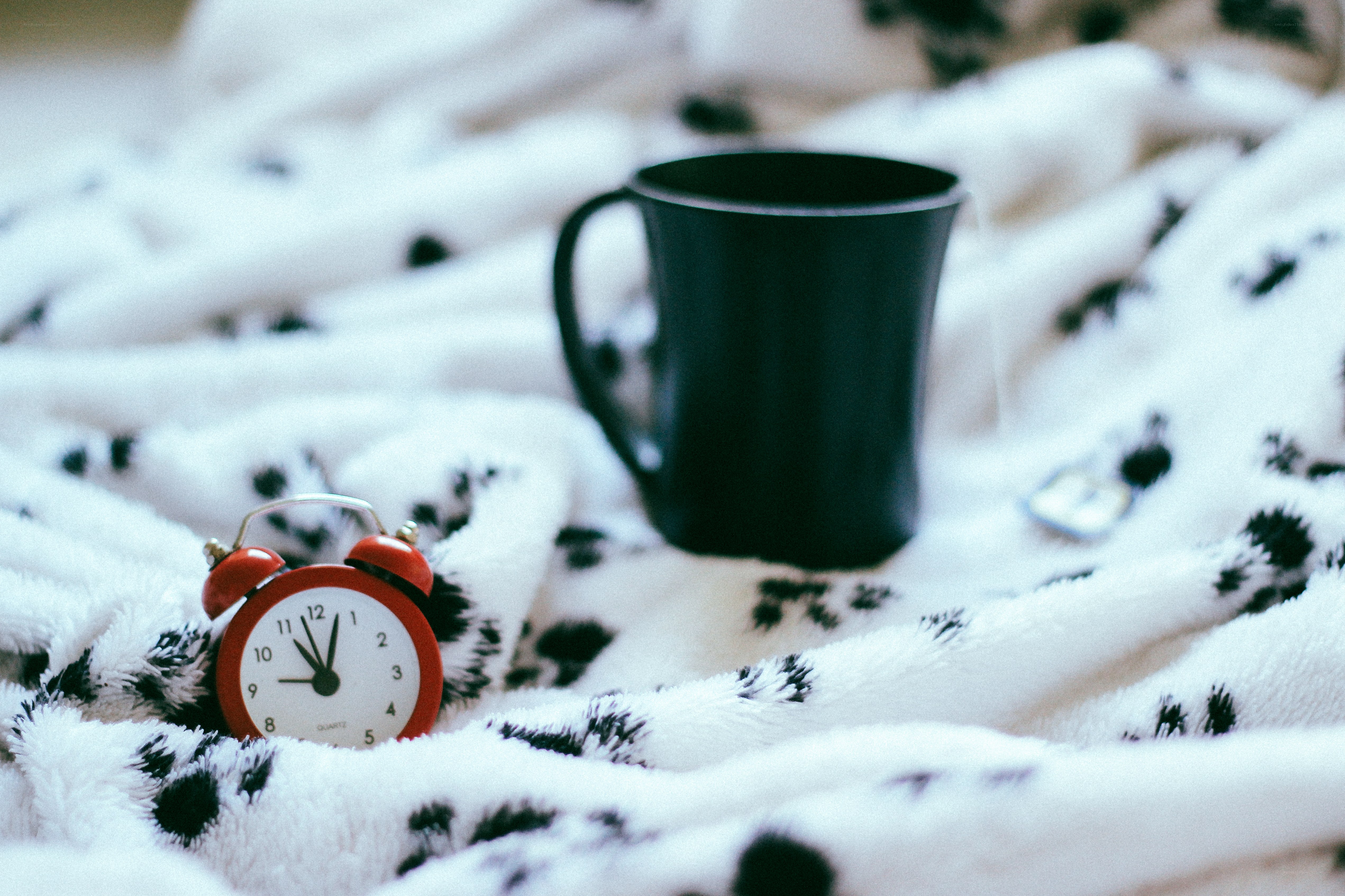 Alarm clock and mug on blanket