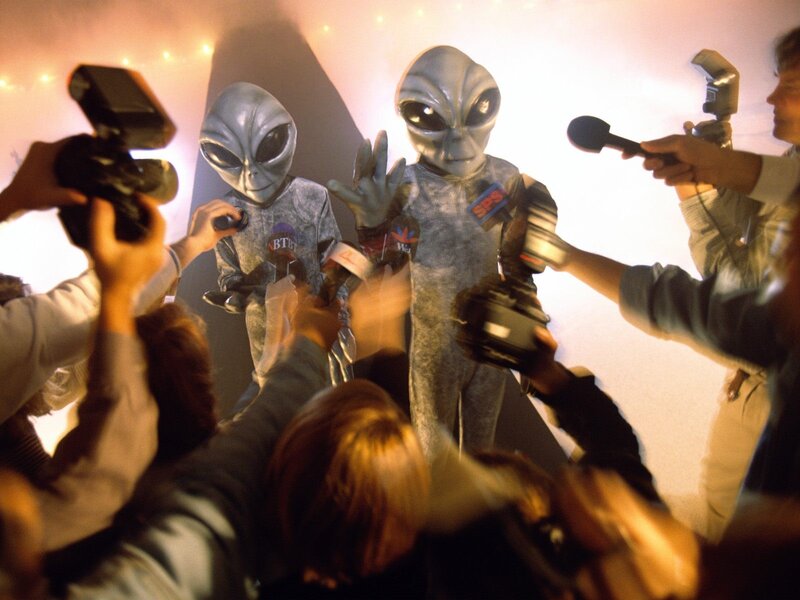 Aliens surrounded by reporters