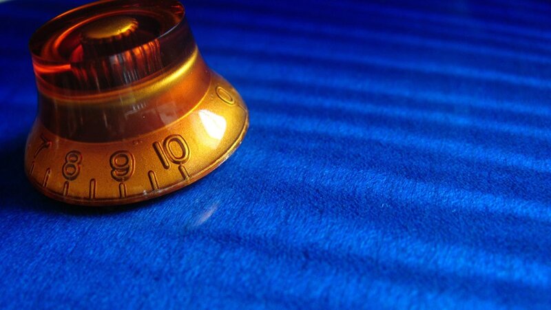amber guitar knob on blue surface