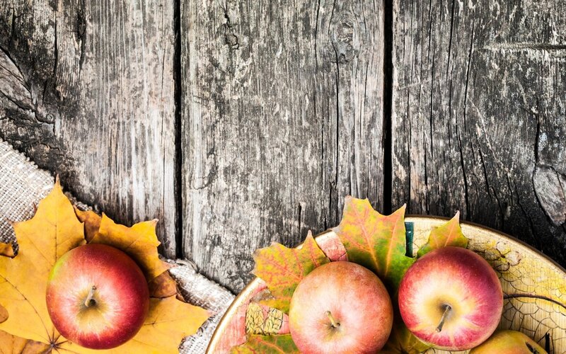 apples and autumn leaves on wood