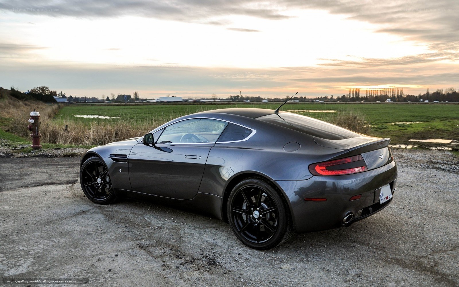 Aston Martin in a field at sunset