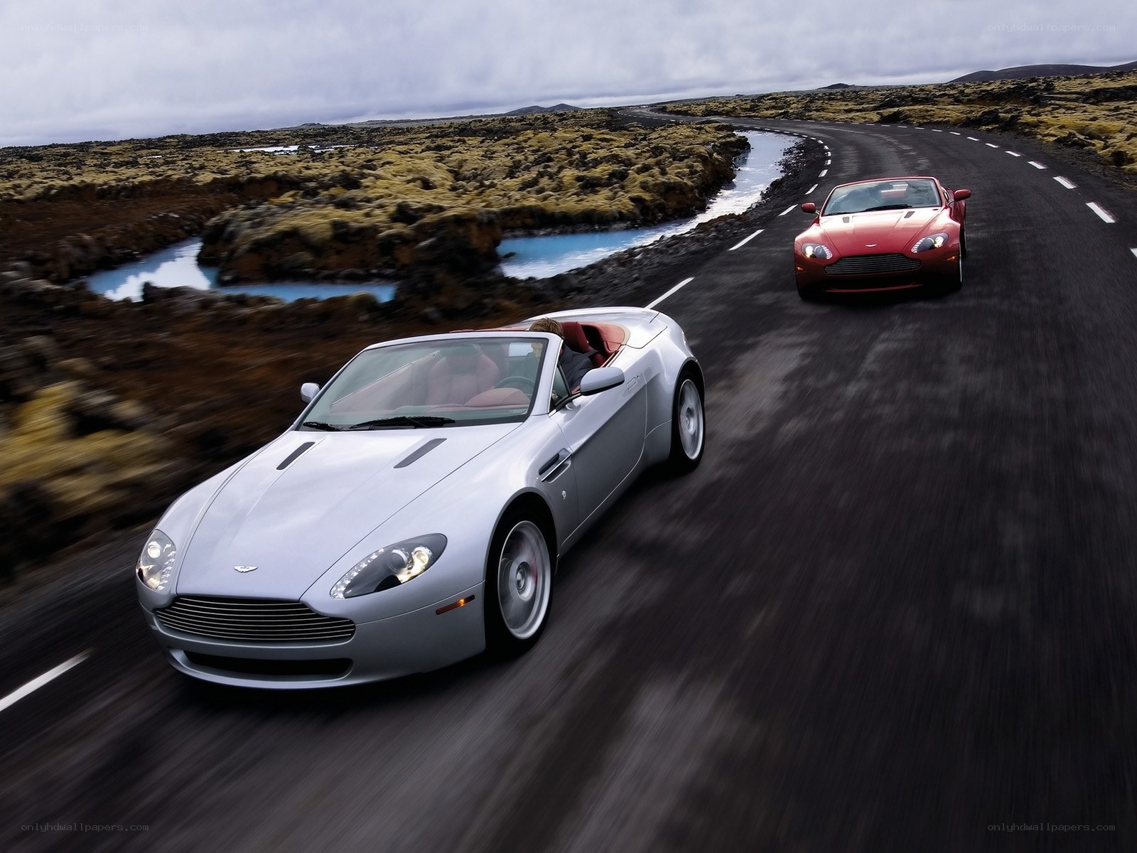 Aston Martin sports cars on a winding road