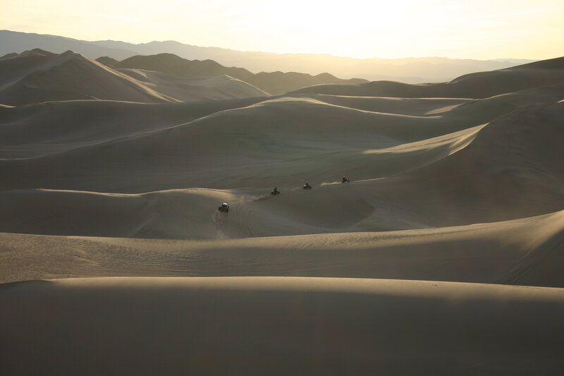 ATVs on sand dunes at sunset