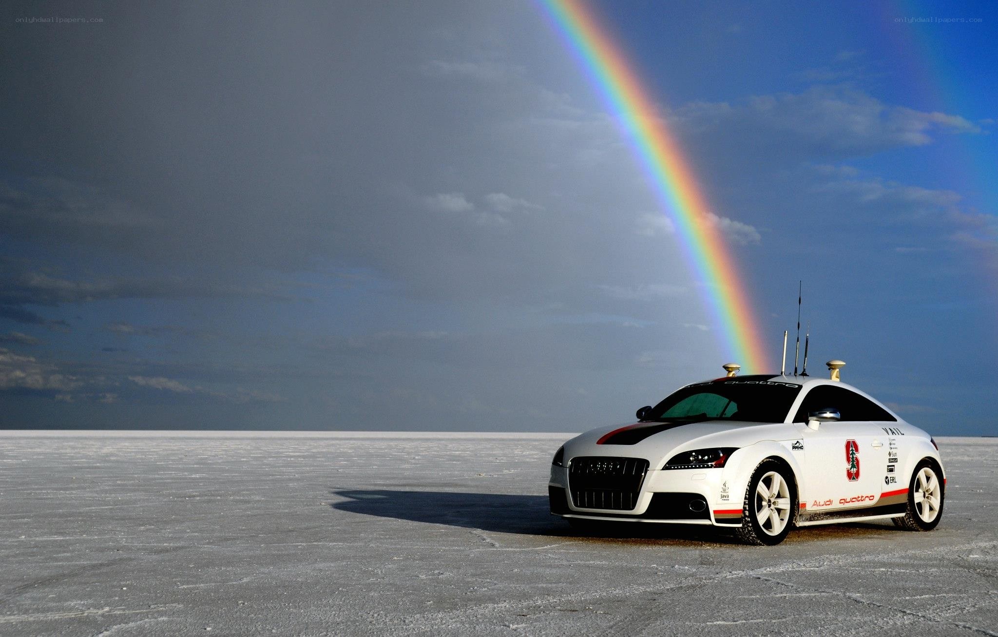 Audi car on salt flat with rainbow