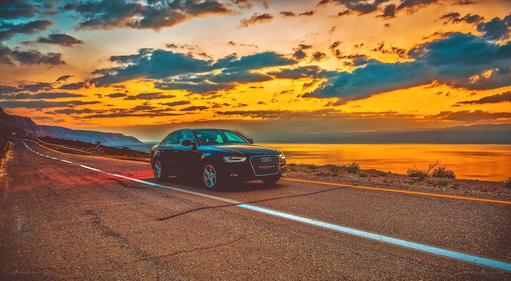 Audi on coastal road at sunset