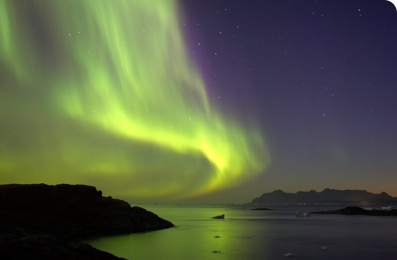 Aurora borealis over rocky coast