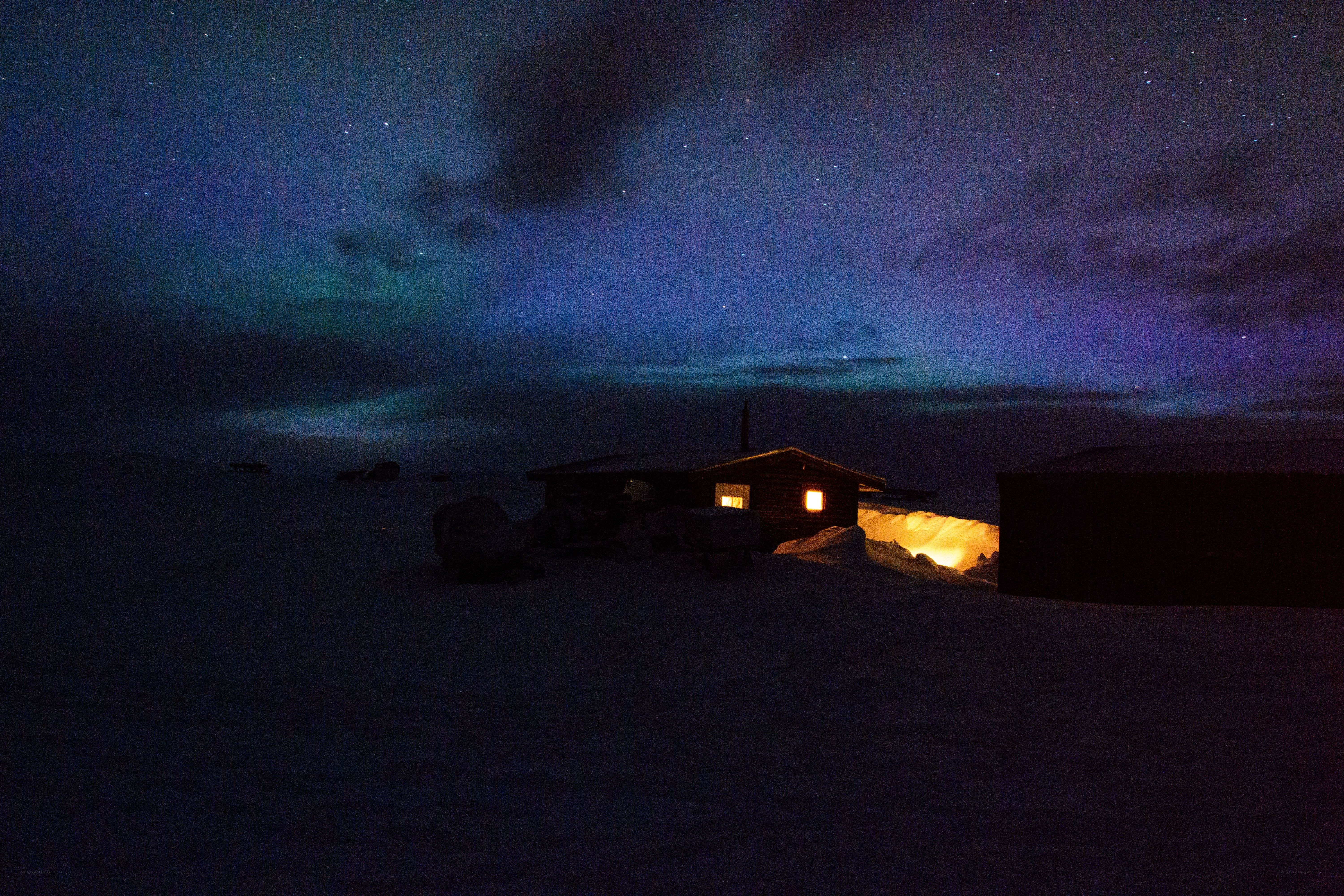 Aurora over a snowy cabin