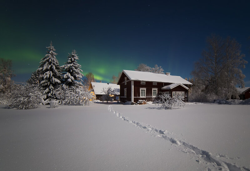 Aurora over a snowy cabin