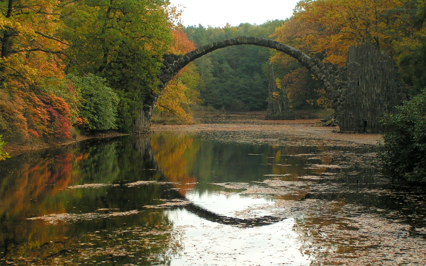 Autumn bridge over calm water