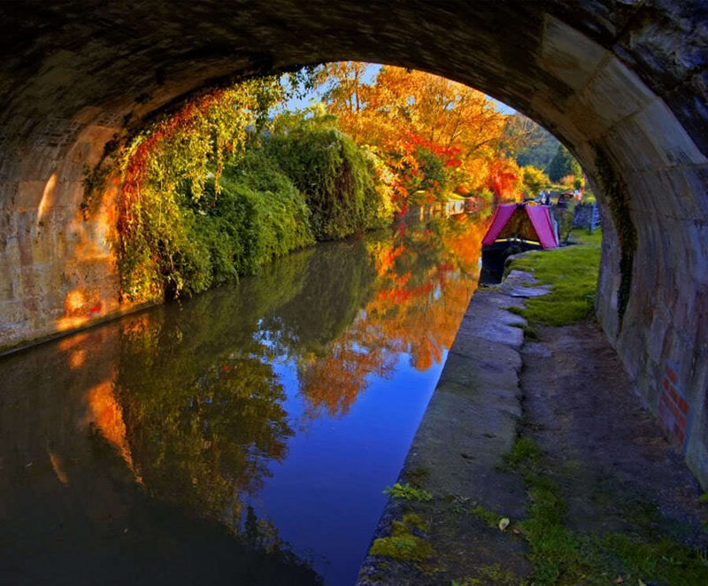 Autumn canal under stone bridge