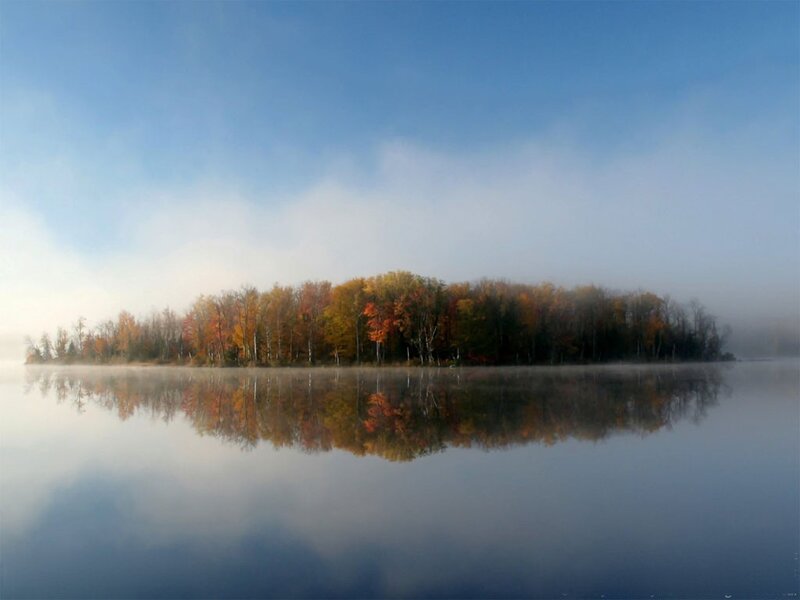 Autumn island in misty lake