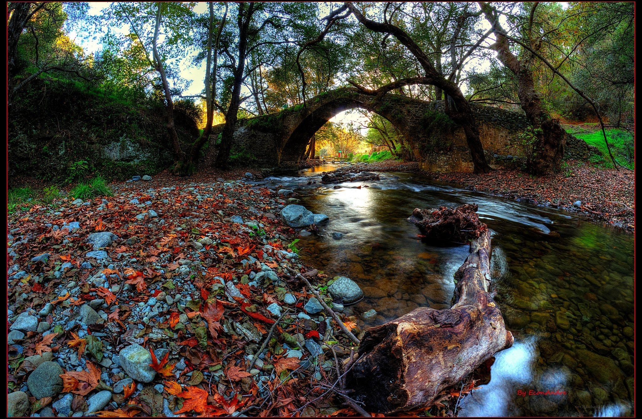 Autumn stream under stone bridge