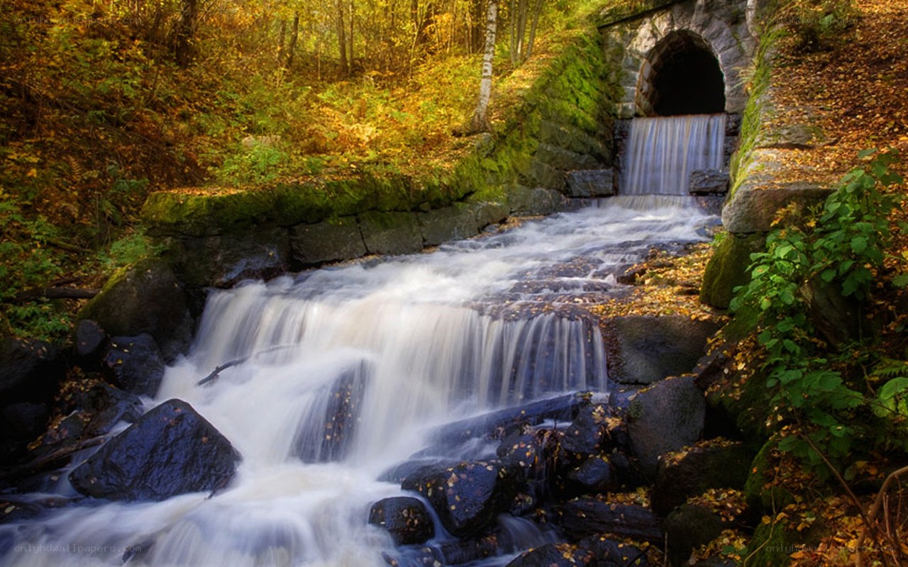 Autumn waterfall under stone bridge