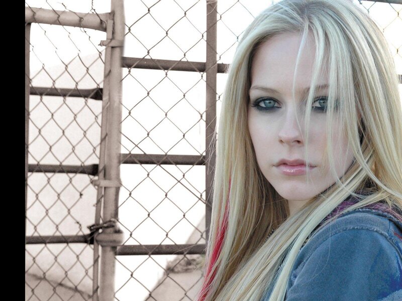 Avril Lavigne by a chain-link fence