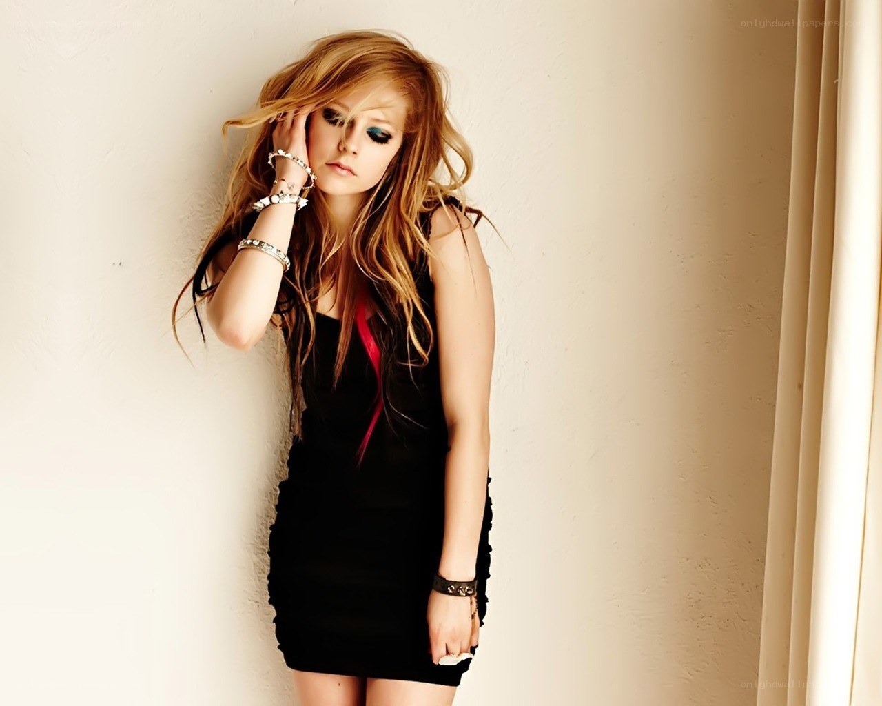 Avril Lavigne posing against a wall