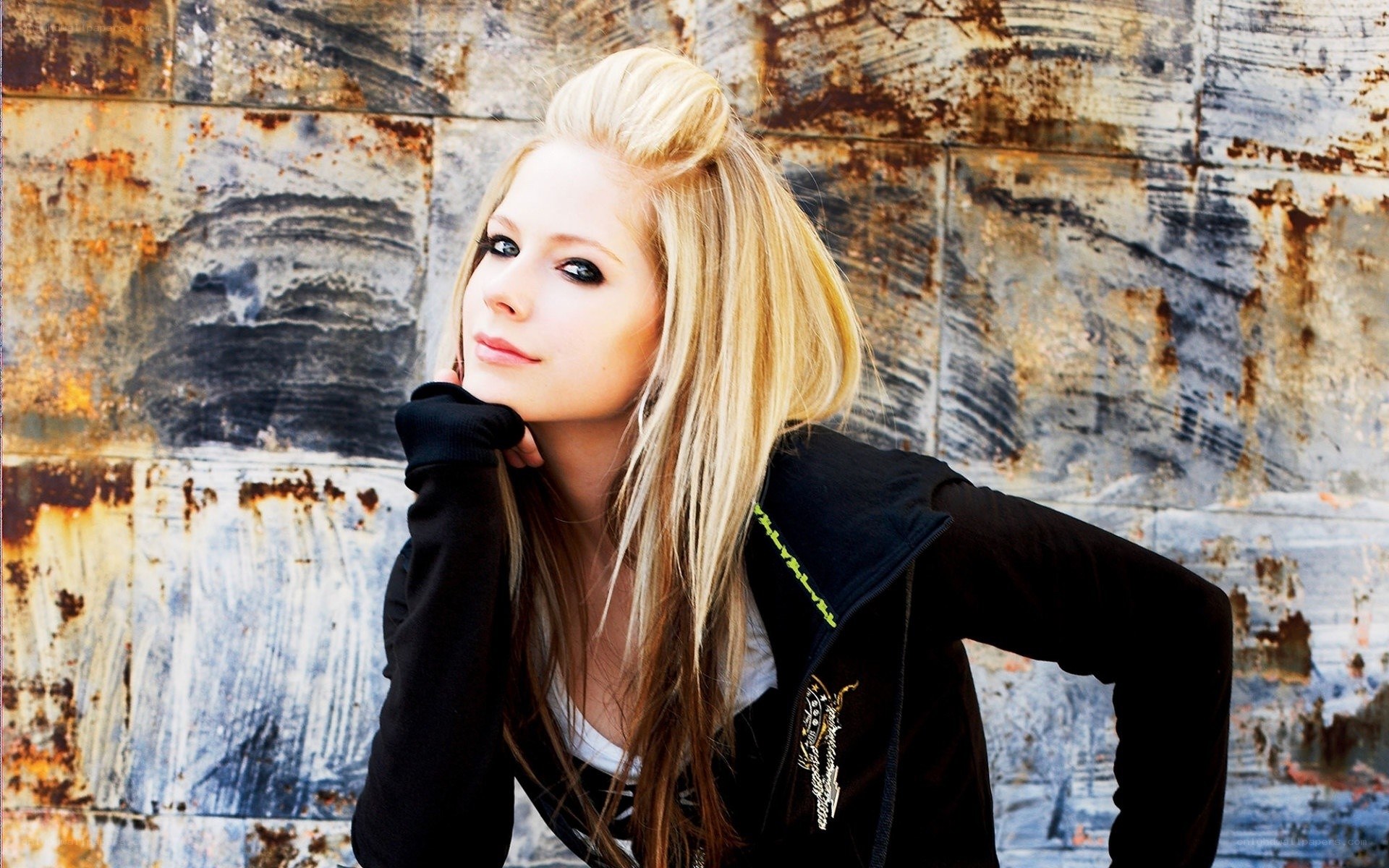 Avril Lavigne posing against rusted wall
