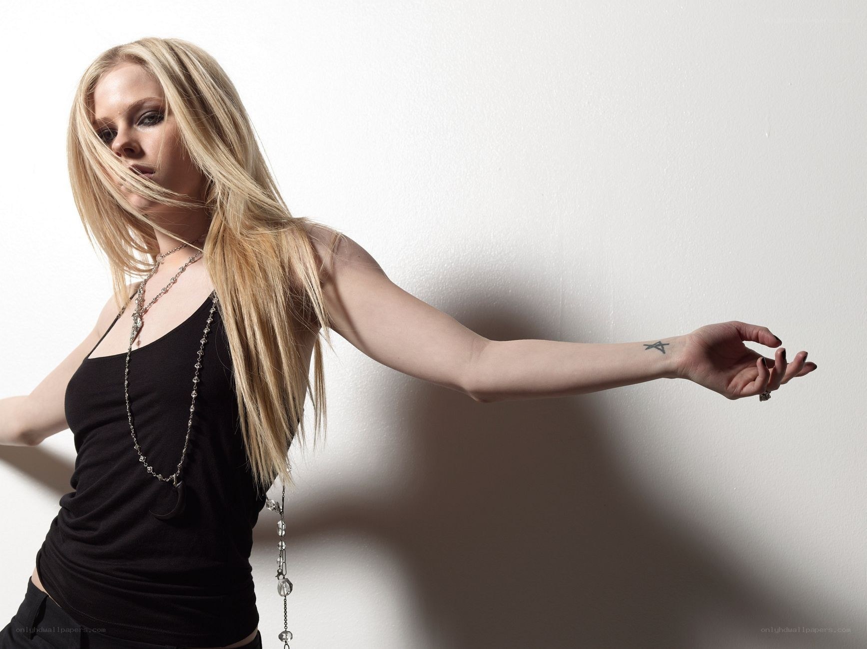 Avril Lavigne posing against white wall