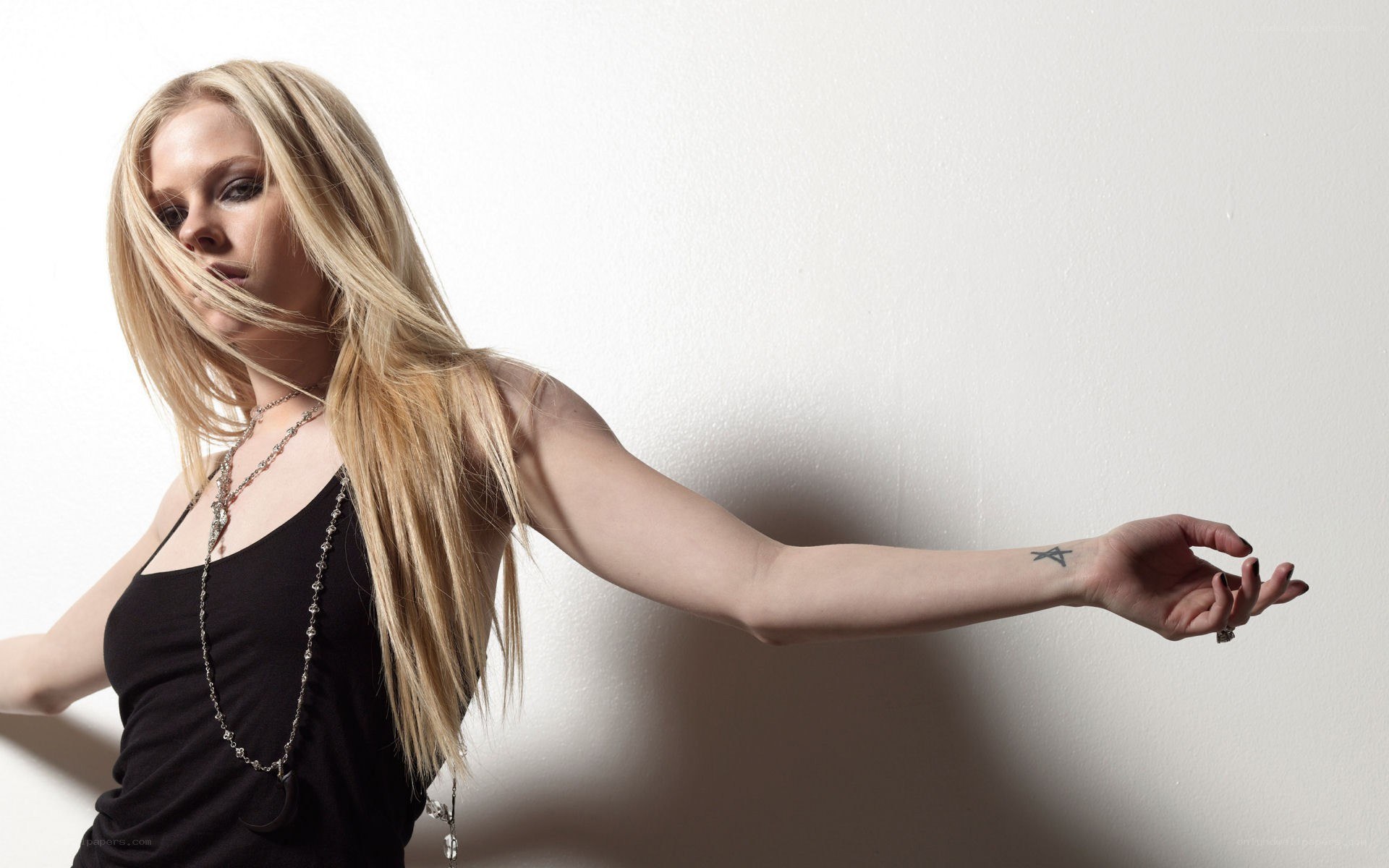 Avril Lavigne posing against white wall
