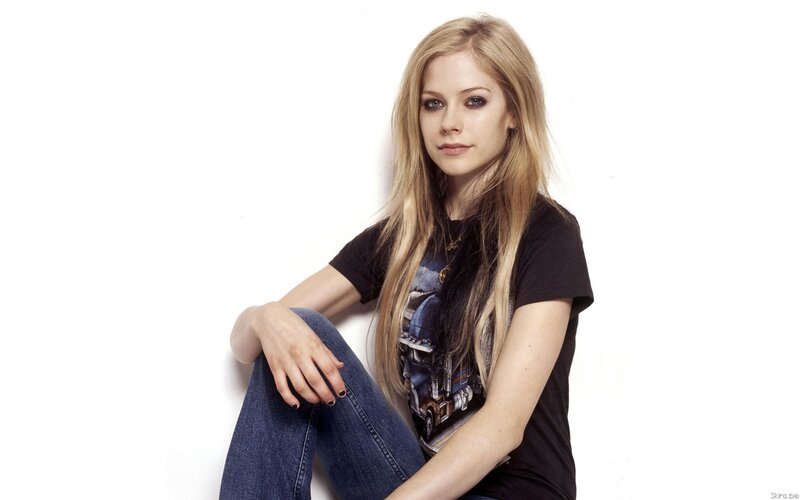 Avril Lavigne sitting against white wall