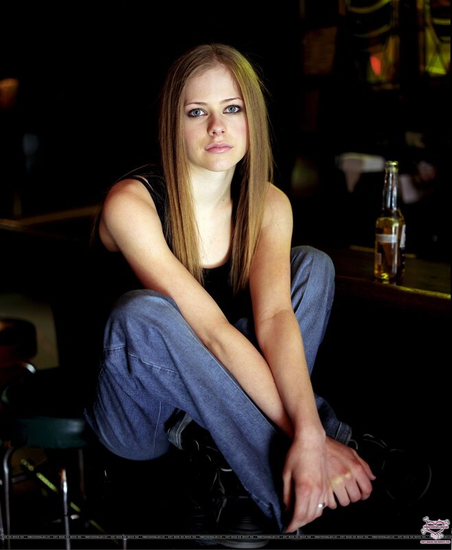 Avril Lavigne sitting on a stool
