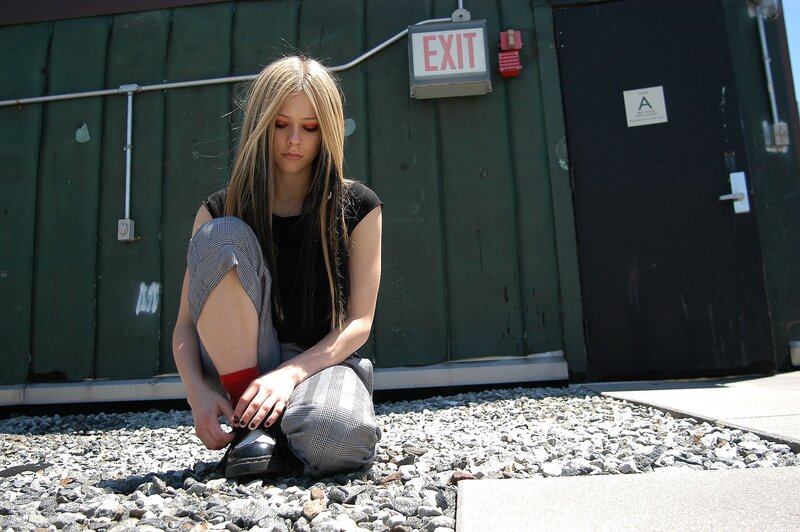 Avril Lavigne sitting on gravel