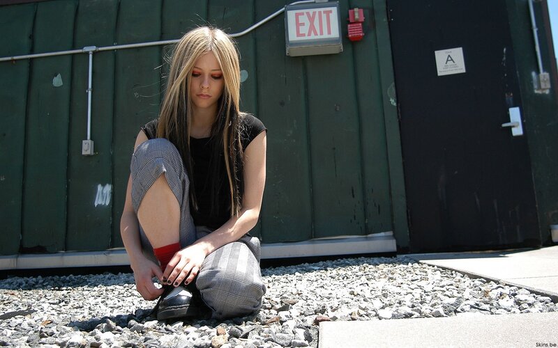 Avril Lavigne sitting on gravel