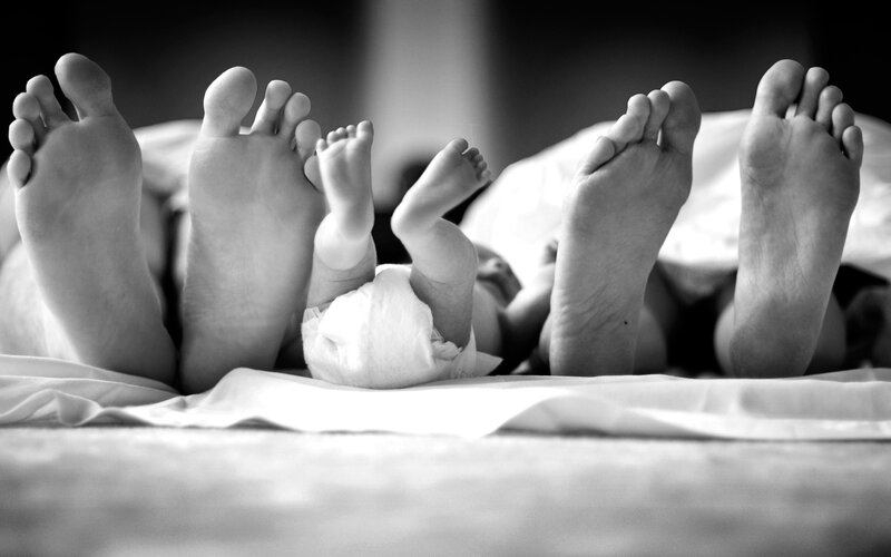 Baby Feet Between Adult Feet — Black
