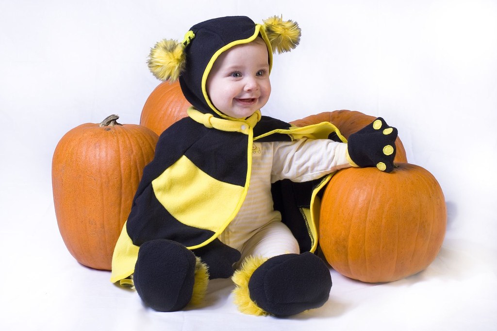 baby in bee costume with pumpkins