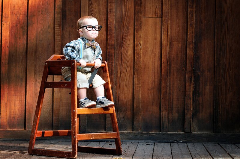 Baby in glasses on high chair