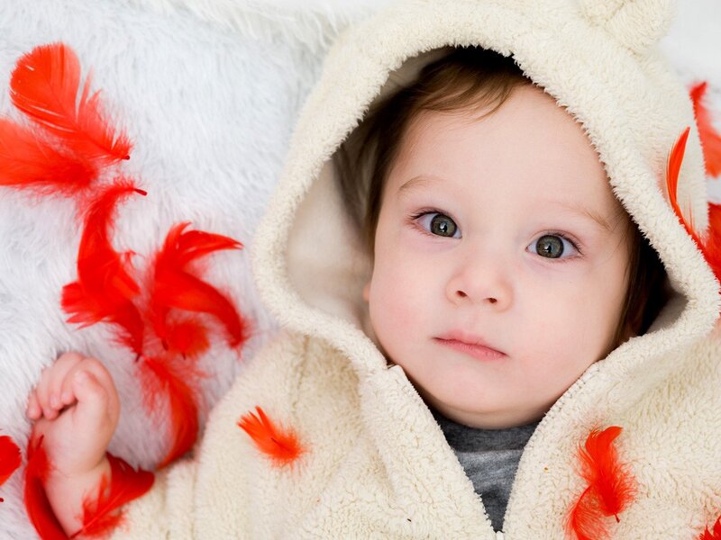 baby in hooded coat with feathers