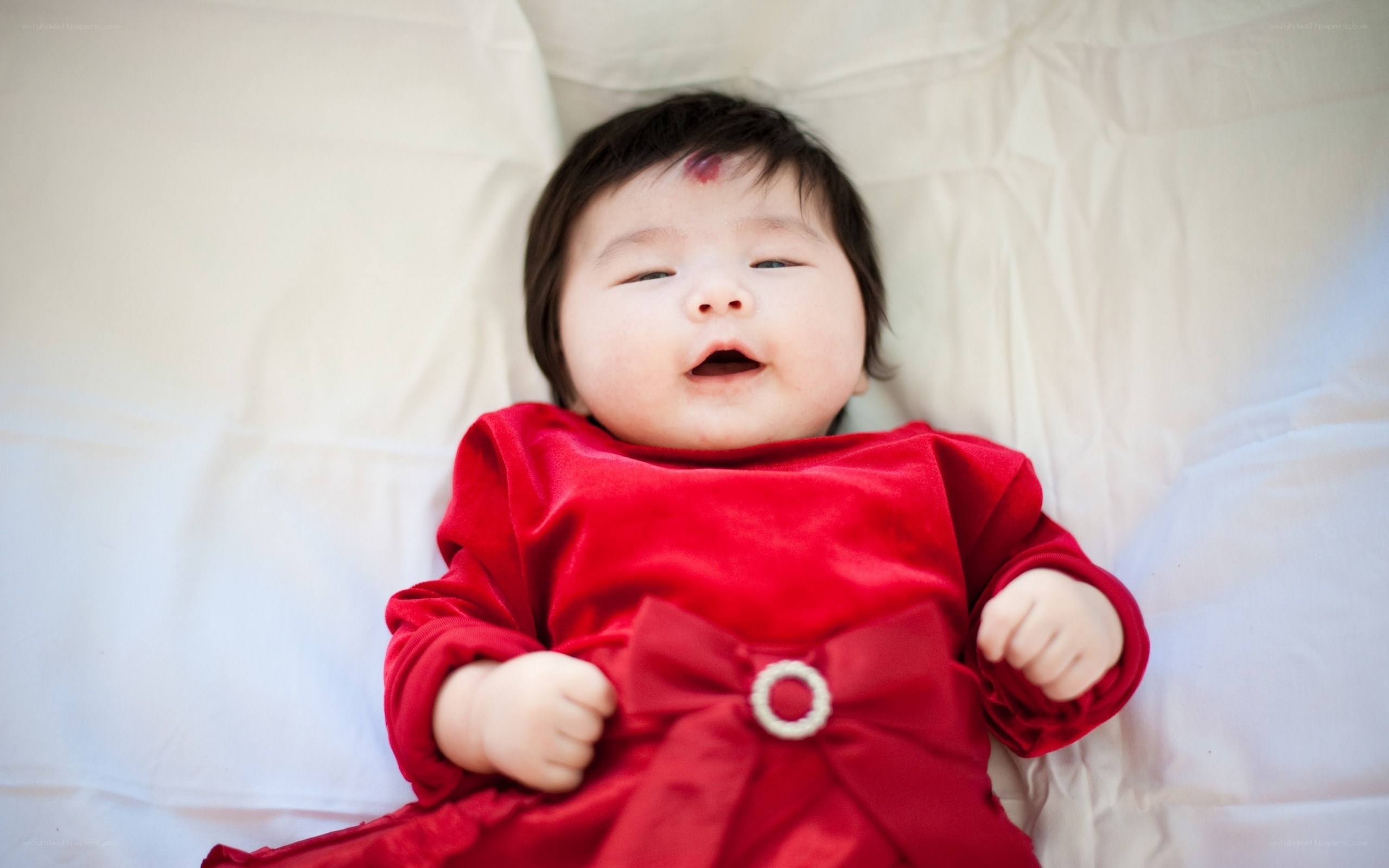 Baby in red dress lying down