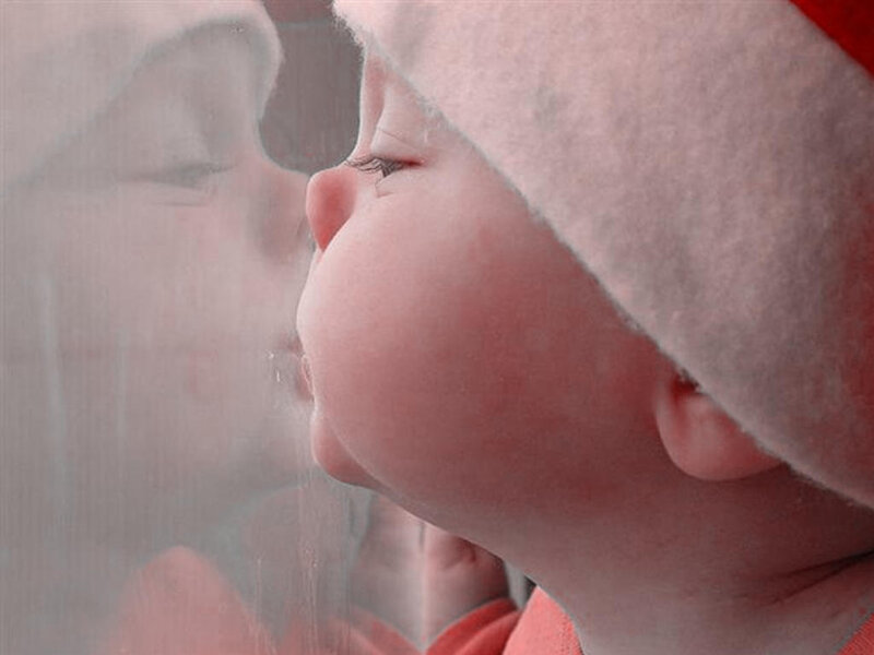 baby in santa hat looking out window