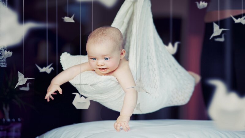 Baby in white hammock with origami